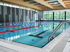 Wewnętrzny basen sportowy. Na pierwszym planie aluminiowa drabinka prowadząca do basenu.
