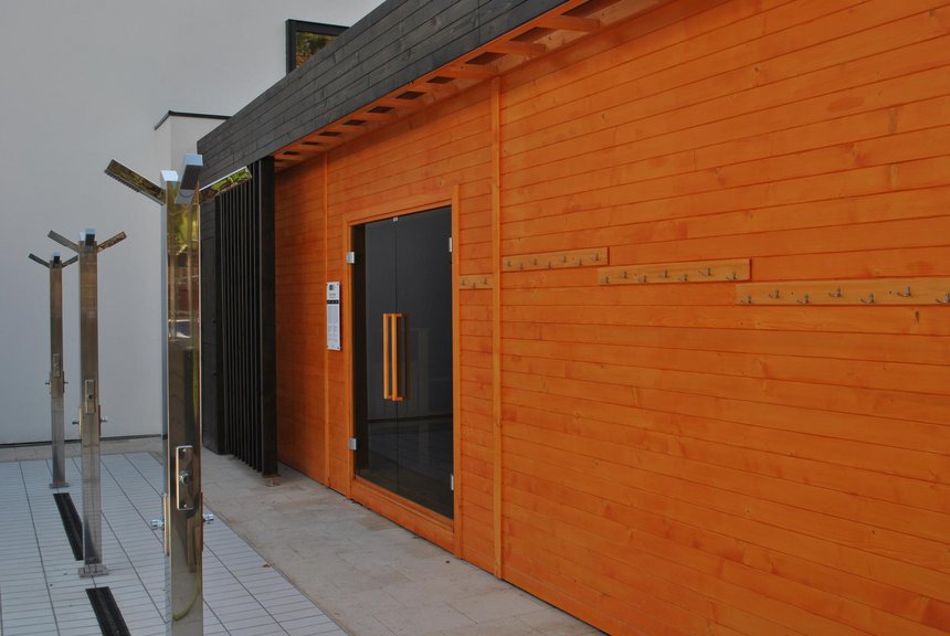 Zewnętrzna duża sauna fińska, a przed wejściem do niej trzy poczwórne prysznice zewnętrzne.