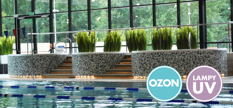 Trzy wanny jacuzzi otoczone biało-szarą mozaiką ceramiczną. W tle przeszklona ściana hali basenowej. W prawym dolnym rogu znaki informacyjne: OZON i LAMPY UV.