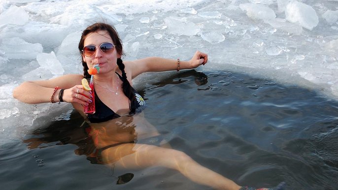 Saunamistrzyni Mariola Żurek. Młoda brunetka zanurzona w przerębli sączy kolorowego drinka. Ma na sobie czarny kostium kąpielowy i okulary przeciwsłoneczne. 