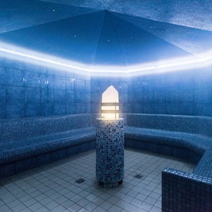 Wnętrze krystalicznej sauny parowej, w centralnym punkcie stoi podświetlany kryształ na ceramicznym podeście. Dookoła sauny dostępne są ceramiczne siedziska.