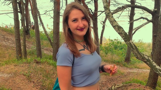 Saunamistrzyni Sandra Kalisz, blondynka mająca włosy do ramion ubrana w krótki jasnofioletowy top odkrywając brzuch. Pozuje na tle drzew, w tle widać jezioro. Kobieta w lewej dłoni trzyma wafelek. Na klatce piersiowej widoczny fragment tatuażu. 